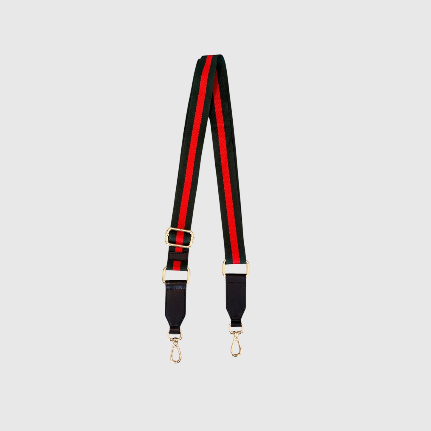 A striped shoulder strap featuring the iconic green and red web stripe pattern, black leather ends, and gold-tone hardware, shown against a light gray background.
