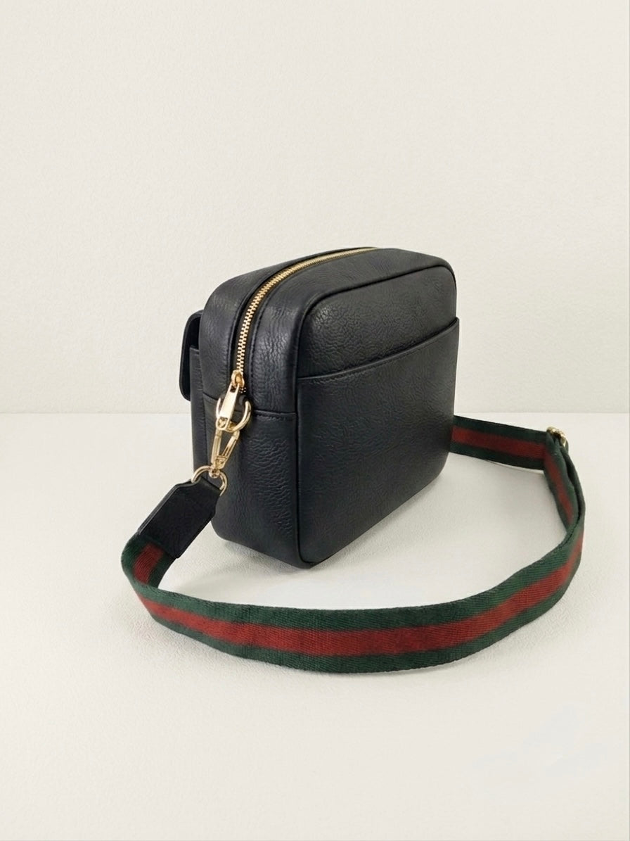 A black leather crossbody phone bag with a green and red striped web stripe shoulder strap and gold-tone hardware, shown on a plain white background.