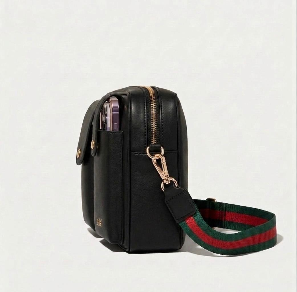 Stile' Alina Crossbody Bag in black genuine leather, side view showing zip closure, gold-tone clasp and striped woven strap with phone in exterior pocket