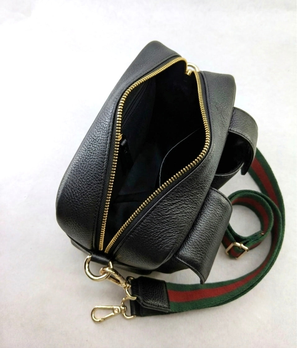 Black genuine leather shoulder bag with a gold-tone zipper, shown open to reveal the interior. The bag features a green and red striped web strap with gold-tone hardware, photographed on a light gray background.