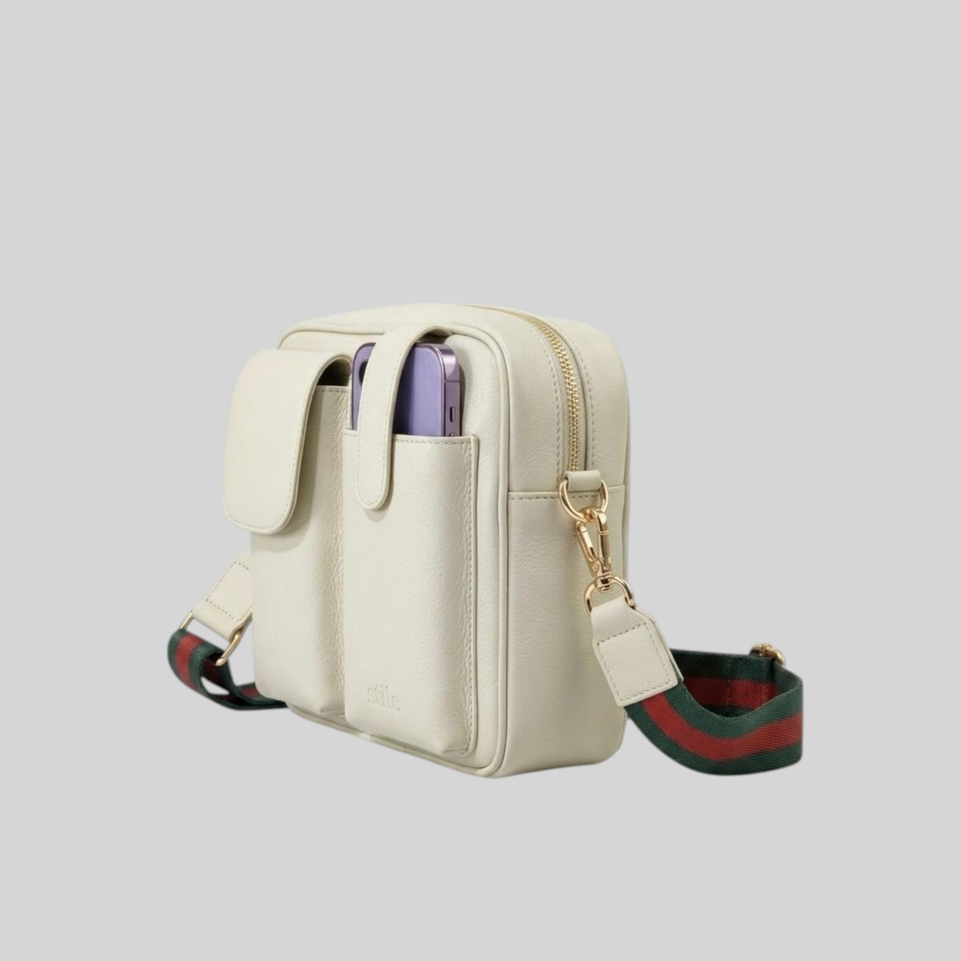 An Ivory leather crossbody phone bag with a green and red web stripe patterned strap, gold-tone hardware, and a zippered main compartment, shown on a solid gray background.