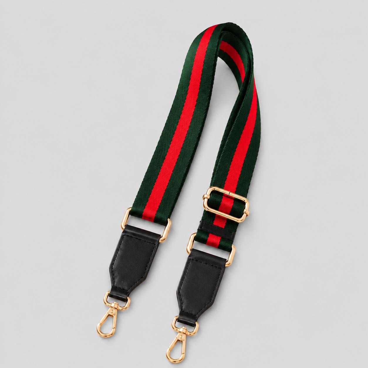 A striped shoulder strap with a green and red web stripe pattern, black leather end caps, and gold-tone metal hardware, shown on a light gray background.